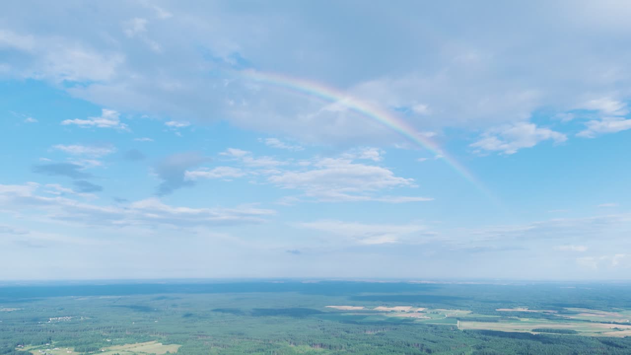 Rainbow above green woodland of Lithuania, aerial drone view