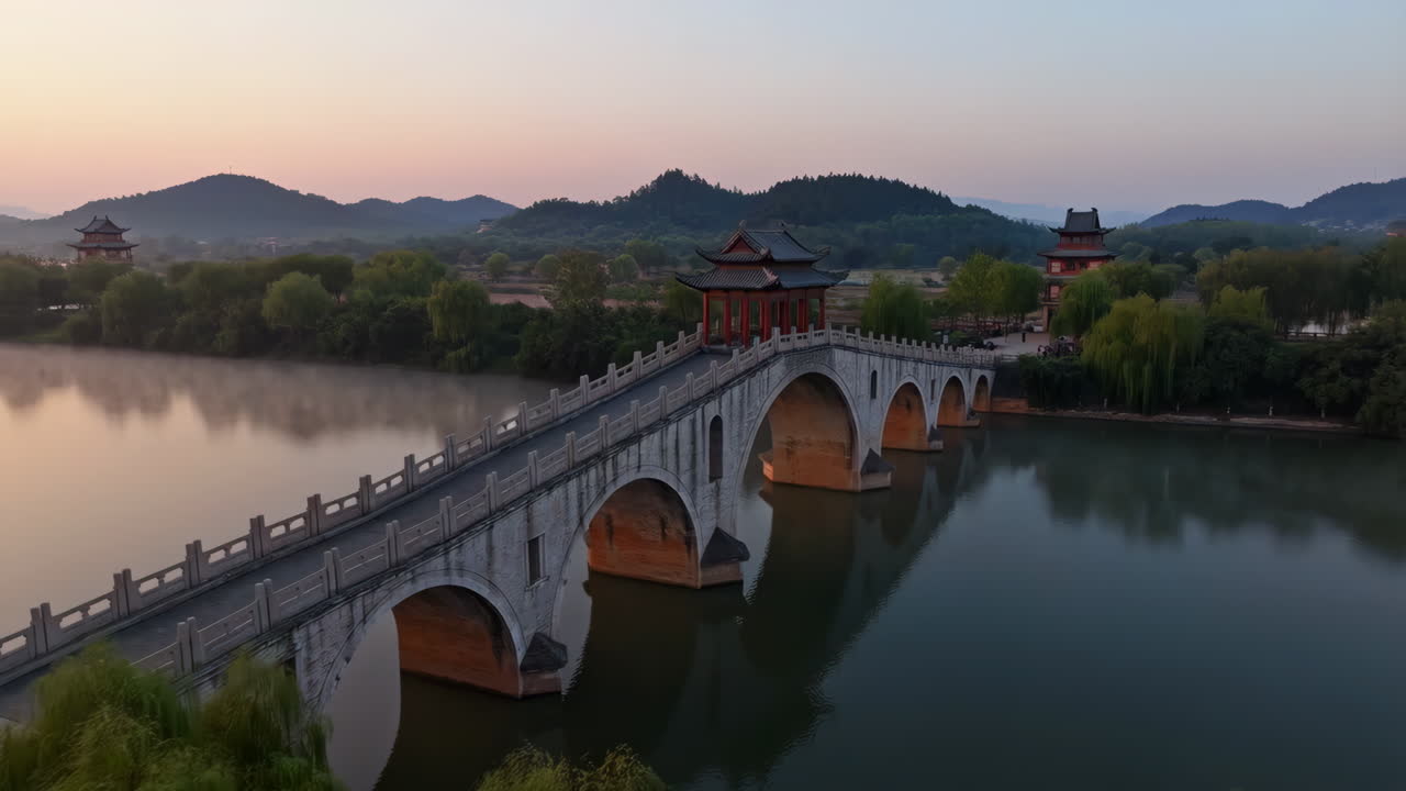 Traditional Chinese Stone Bridge and Pavilions over a Calm Lake at Dawn