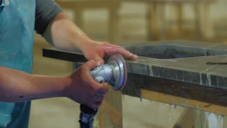 worker polishing edge of granite kitchen countertop - quartz -rock with a polisher with water in a warehouse