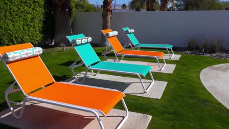 colorful lawn chairs sit around a pool at a palm springs home