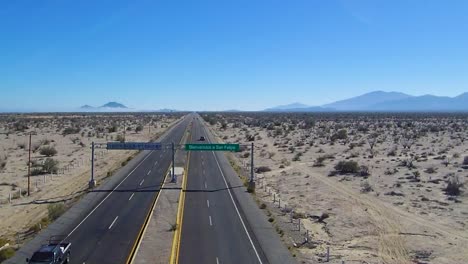 view of a drone descending over a highway showing a sign that says "bienvenidos a san felipe