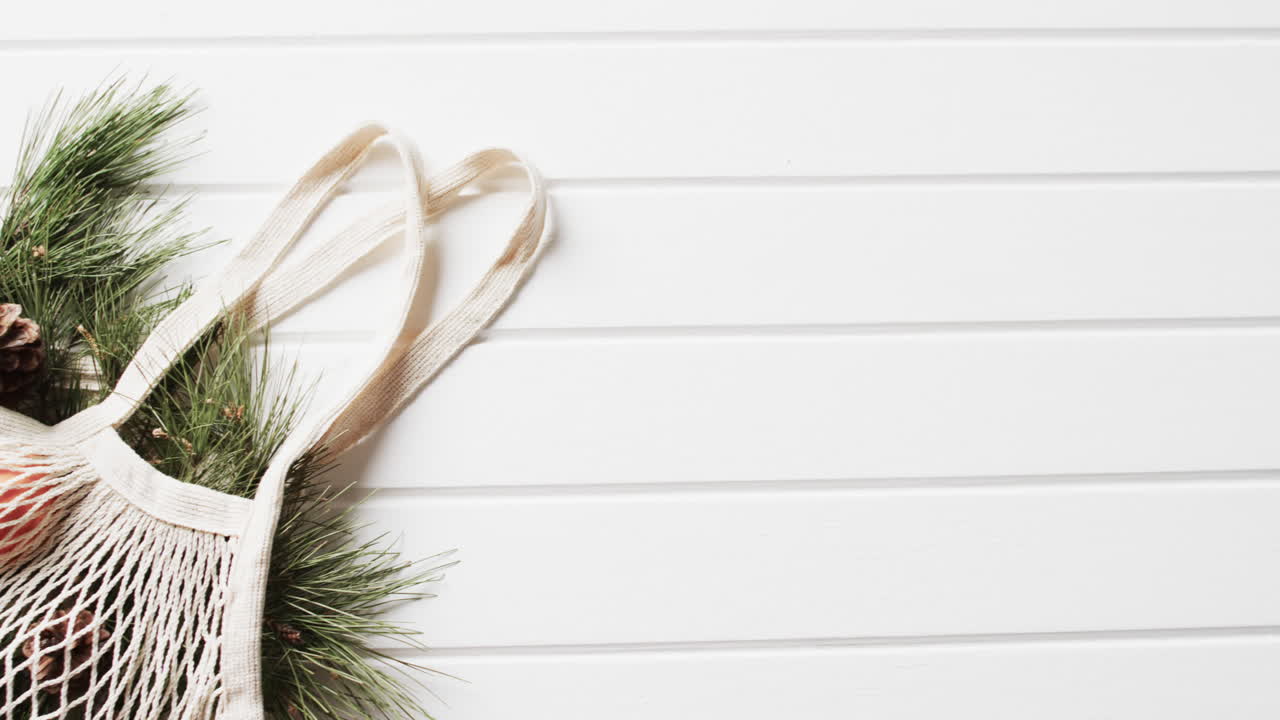 video de una bolsa de red con decoraciones de navidad y ramas de abeto y copia de espacio en fondo blanco