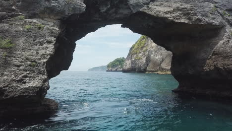 aerial flight through eroded sea cave on bali's