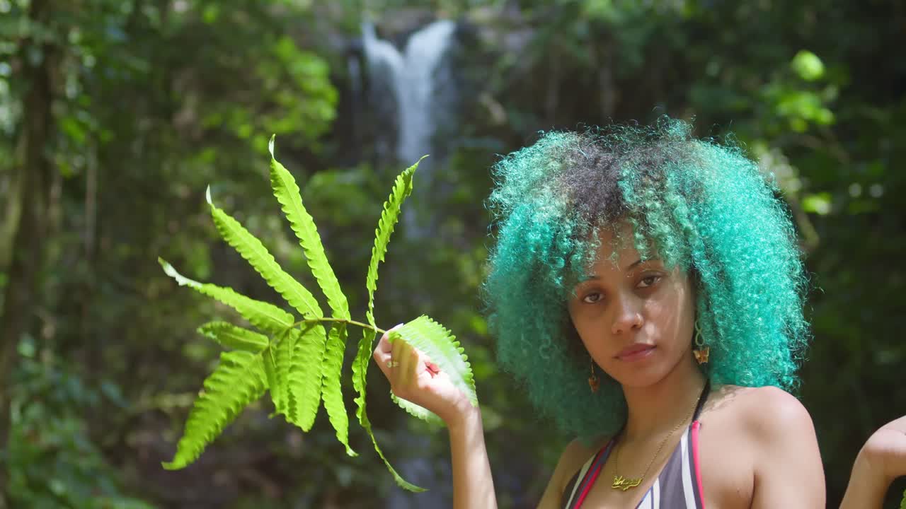 배경에 폭포가 있는 자연 속의 소녀의 얼굴 클로즈업