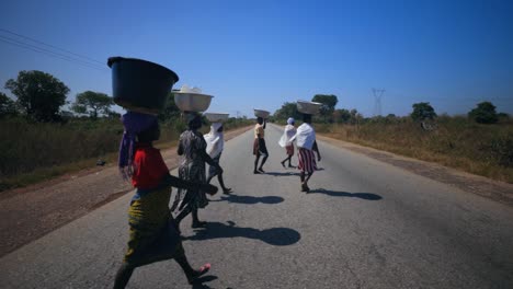 african women carrying buckets with water on their head in ghana