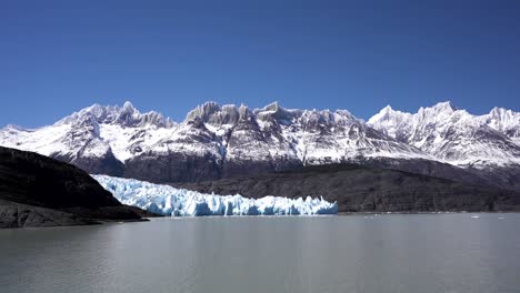 turismo de un lago glaciar con picos nevados de montaña en el fondo