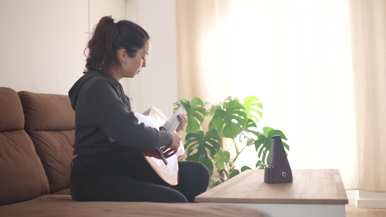 Young woman practicing guitar at home for relaxation