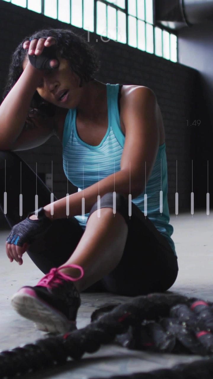 Vertical video: Fitness pro finishing rope set sitting wiping sweat while HR bars tracking recovery