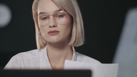 focused business woman working with documents front laptop in night office.