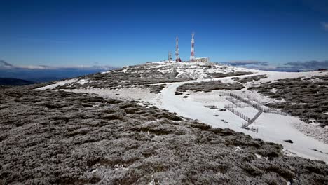 toma aerea ascendiendo una montaña nevada hacia unas antenas en la cima de la montaña en manzaneda, galicia