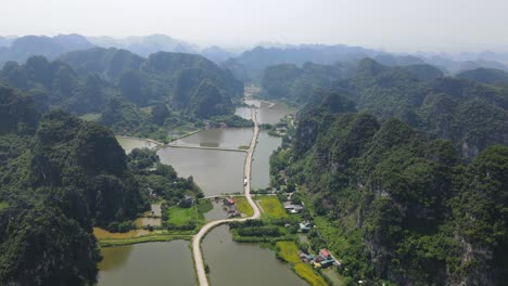 drone shot of beautiful karst landscape with winding road in the middle and lake on both sides ninh binh viet nam