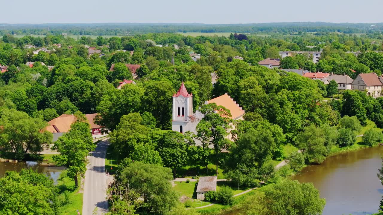 Lush green aerial scene of Aizpute town with church on bright sunny summer day