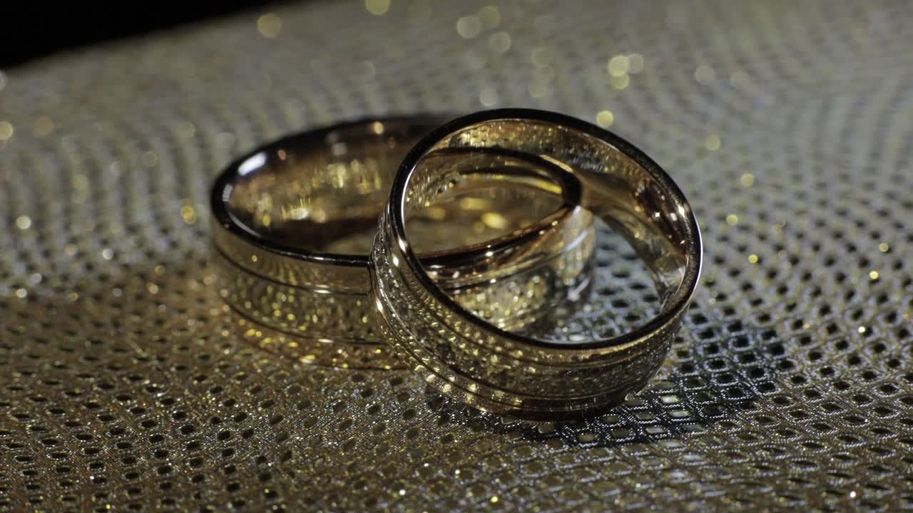 Wedding gold rings lying on shiny glossy surface. Shining with light. Close-up