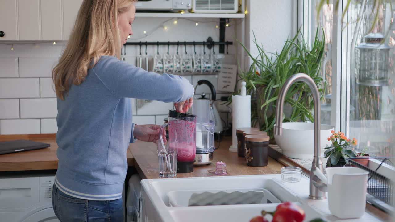 Woman making smoothie in kitchen