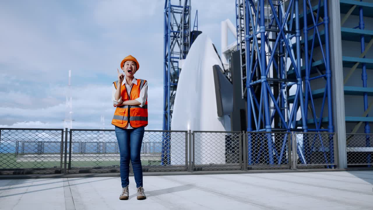cuerpo lleno de ingeniera asiática con casco de seguridad pensando y mirando a su alrededor luego levantando su dedo índice mientras estaba de pie con el transbordador espacial