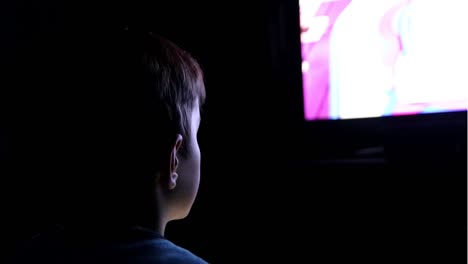 short lit boy highly concentrated on high definition screen projected on his face while playing electronic console video games