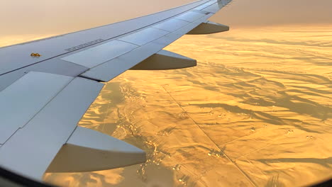 on an airplane looking down at the landscape below. beautiful plane ride at sunset, a time-lapse at golden hour.