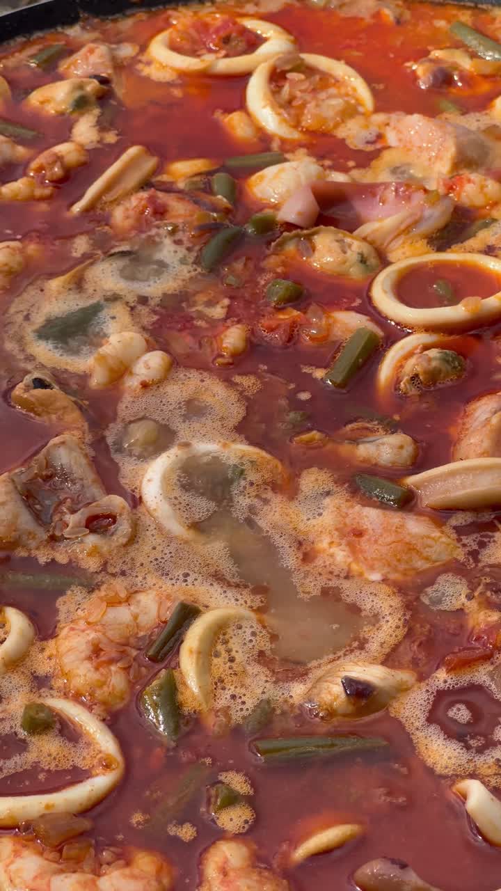 Spicy seafood stew with squid, shrimp, and vegetables boiling in a pot