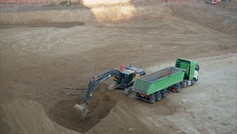 excavator digging and loading dirt into dump truck on a large construction site. sitework preparation. preparatory work done on a construction site before the actual building. heavy equipments.