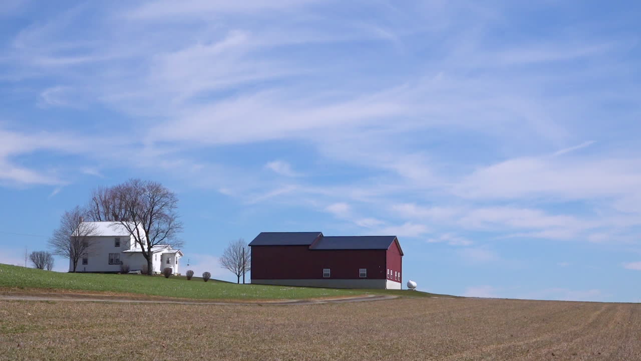 una toma muy amplia de una granja amish o menonita aislada en el medio oeste de américa con el paso de un carro de caballos