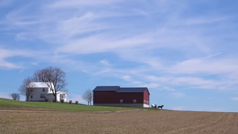 Un-Plano-Muy-Amplio-De-Una-Granja-Amish-O-Menonita-Aislada-En-El-Medio-Oeste-De-Estados-Unidos-Con-Un-Carro-De-Caballos-Pasando