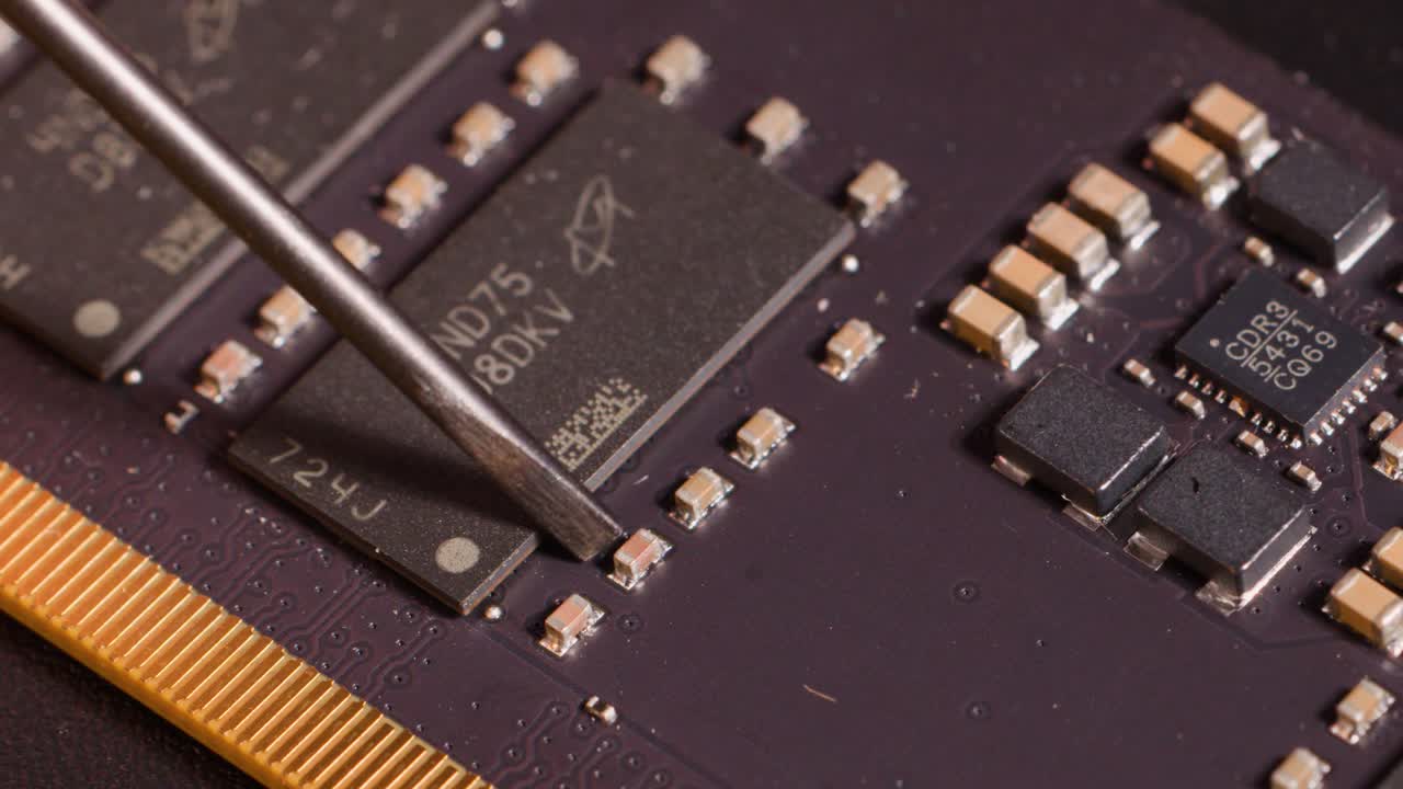 Close-up macro shot of a metal tool inspecting components on a purple computer circuit board