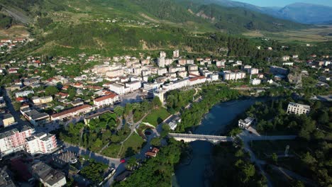 bridge of permet over emerald vjosa river green park red roses white buildings spring panorama