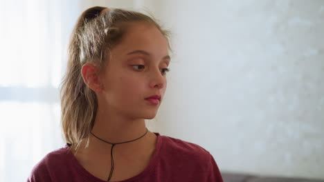 cute girl looking thoughtfully at someone in the background, soft light illuminating her face, indoor setting with gentle atmosphere, concerned or curious expression, calm moment
