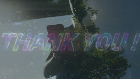 animation of thank you over african american man using smartphone over field