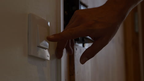 hand switches lights off in room to save money on home electricity usage