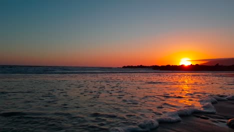 Very-low-gimbal-shot-of-beach-at-sunset-following-waves-crashing-at-San-Buenaventura-State-Beach-in-Ventura,-California,-United-States