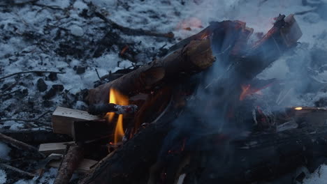 Flame-close-up:-Campfire-burns-wood-on-snow-in-winter-outdoor-scene