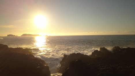 Sunny-calm-ocean-waves-splashing-rocky-shore-of-Ucluelet,-wide-dolly-shot