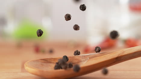 spoon of black pepper falls onto the kitchen countertop, and the spice scatters in macro and slow motion