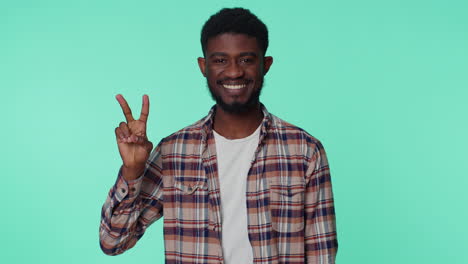 african american smiling man showing victory sign, hoping for success and win, doing peace gesture
