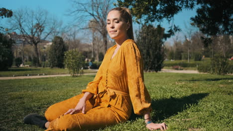 una joven elegante sentada en el césped al aire libre.