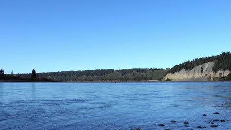 early-morning kayaker paddles upstream on a beautiful mid-winter's day - rakaia river gorge
