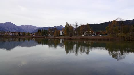 panning shot showing epic mountains and a tranquil lake in the alps in autumn