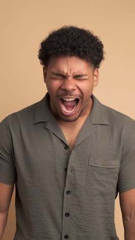 frustrated young man screaming in beige studio