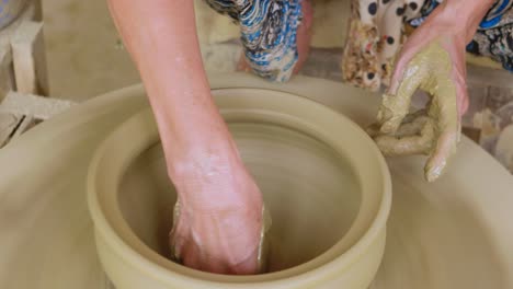 finalizing clay pot on a manual potters wheel with thread