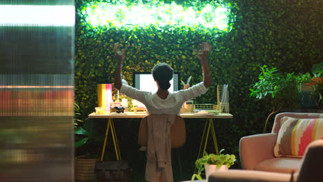 Woman-stretching-at-desk-in-creative-workspace