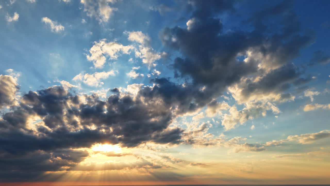Skylapse of dramatic sunset and shifting clouds over coastal skyline at golden hour