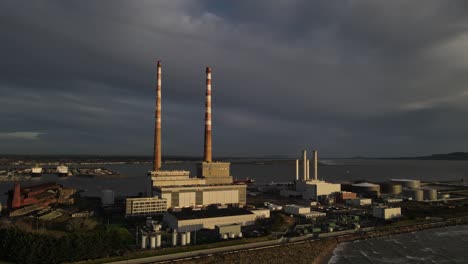 the poolbeg towers in dublin ireland with view of dublin port on a dramatic sunset - aerial drone