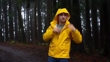 el hombre se atreve a la misteriosa lluvia del bosque, cierra el impermeable amarillo en la incomodidad