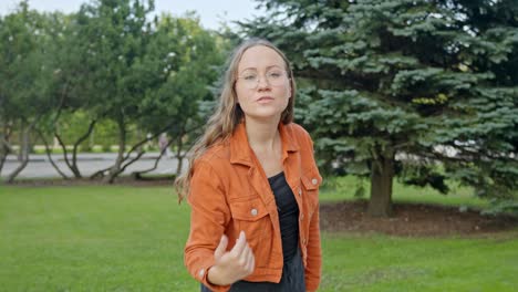 welcoming gesture: brunette beauty waving with a smile in nature