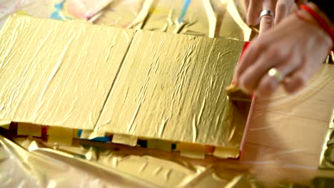 a woman removing painters tape to finish her colorful stripes on a canvas