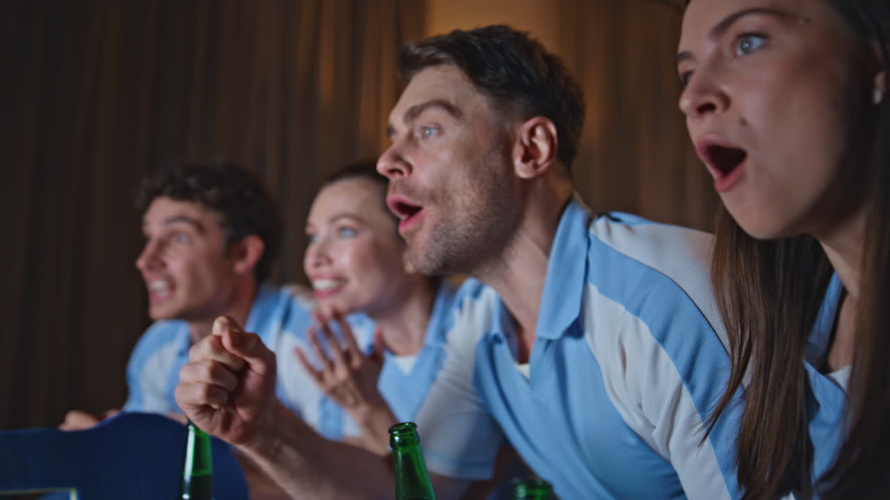 Excited people cheering sport game at evening living room close up. Happy fans
