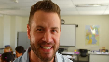 vista frontal de un feliz maestro caucásico de pie en el aula de la escuela 4k