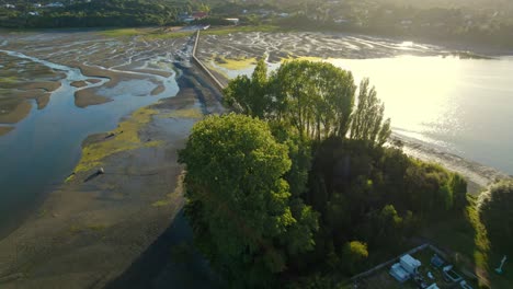 Aerial-view-of-the-Aucar-Island-bridge-with-the-sun-reflecting-on-the-water,-Quemchi,-Chiloe-Chile