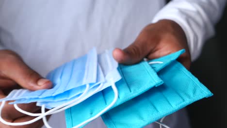 person holding various types of blue face masks